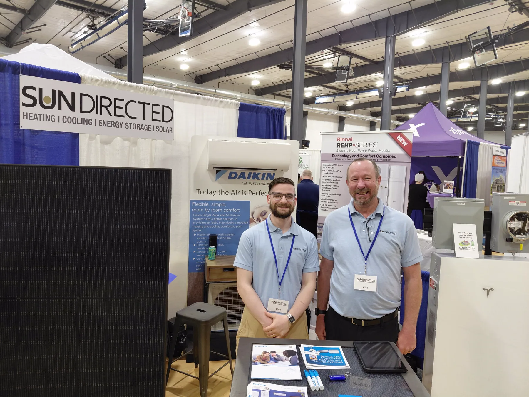 Jacob and Michael at the Sun Directed home show booth, with the branded banner and a Daikin wall unit behind them